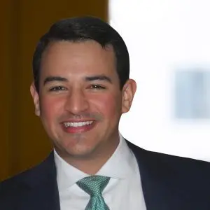 A man in a suit and green tie smiles at the camera, with the focus keyphrase not set and a softly blurred indoor background.