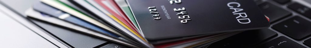 A stack of assorted credit and debit cards is fanned out on top of a laptop keyboard.